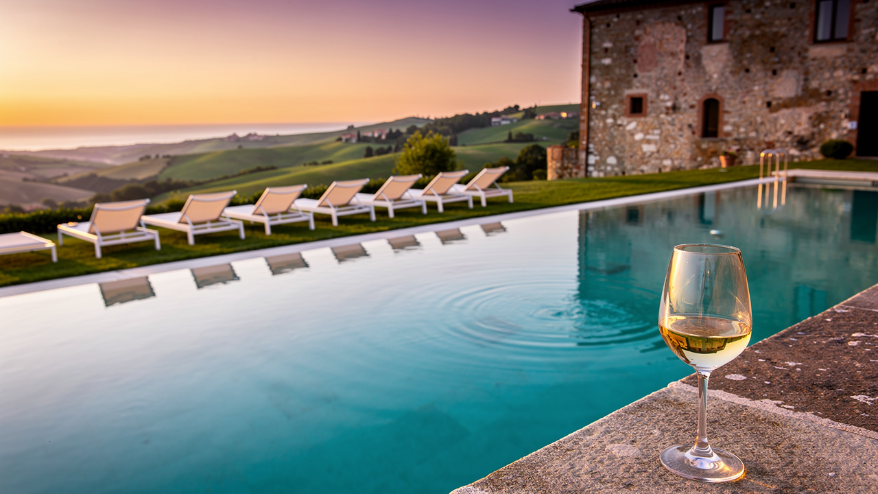 Piscina panoramica al tramonto con vista sulle colline e il mare